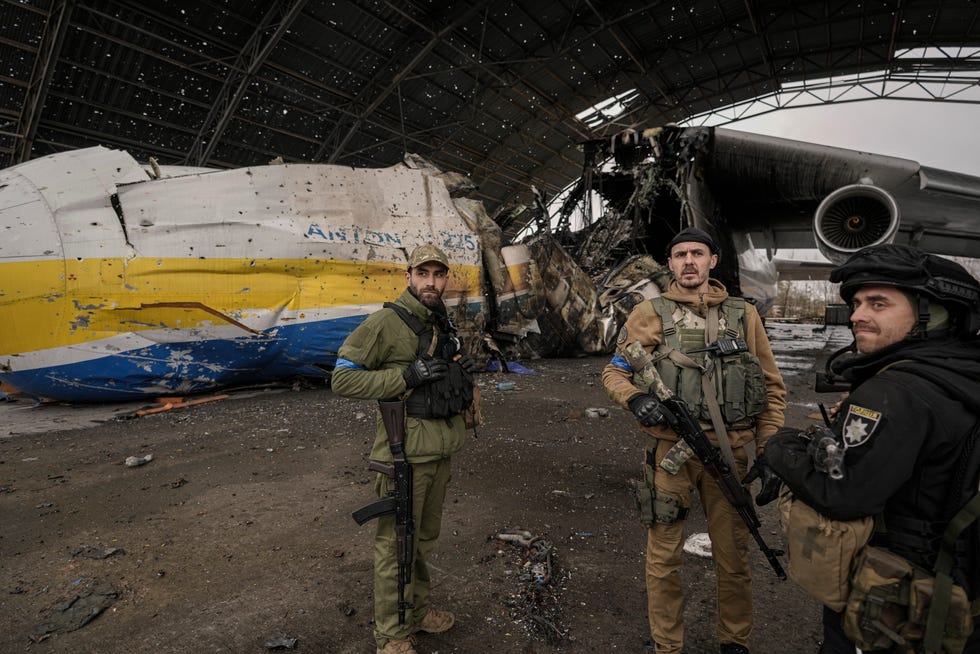 Des militaires ukrainiens se tiennent à côté de l'avion Antonov An-225 Mriya détruit.