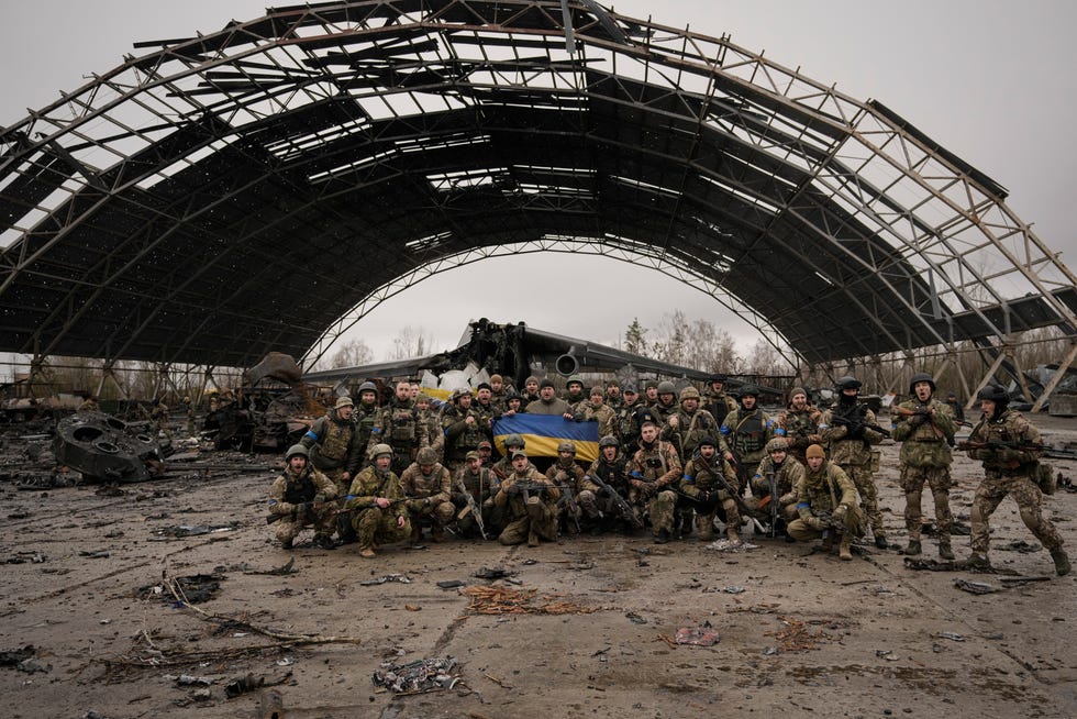 Des militaires ukrainiens crient des slogans patriotiques en toile de fond de l'avion Antonov An-225 Mriya détruit.