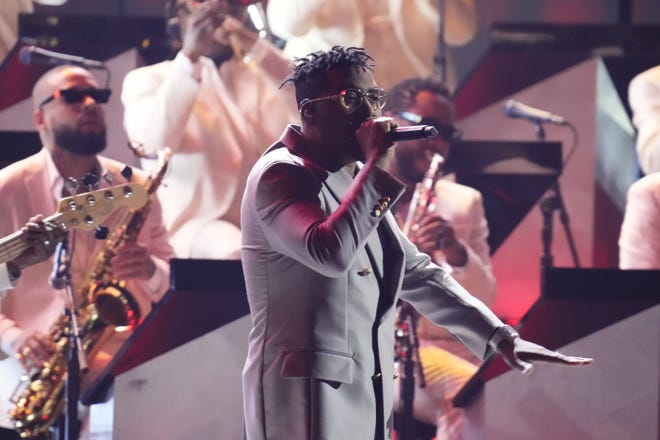 Armed with a full horn section, Nas raps a montage of tracks at the 64th Grammys.