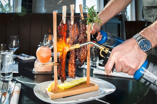 الشيف ديفيد بيرك يدعو إلى خط الغسيل الفيروسي ، طبق لحم الخنزير المقدد المزجج بالقيقب "عندما تطير الخنازير." سيفتتح الشيف النجم مطعمًا على الواجهة البحرية في ليك بارك في عام 2024.