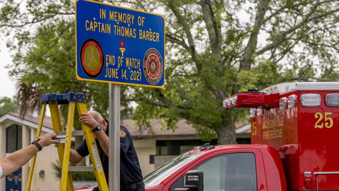 Jacksonville firefighters install a sign honoring Capt. Thomas Barber outside his worksite, Station 25.