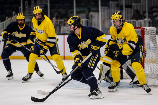 Michigan striker Mackie Samoskevich (11), center, appears to have survived a training session as Wolverines prepare for a Frozen Four match against Denver at TD Garden in Boston on Wednesday, April 6, 2022.
