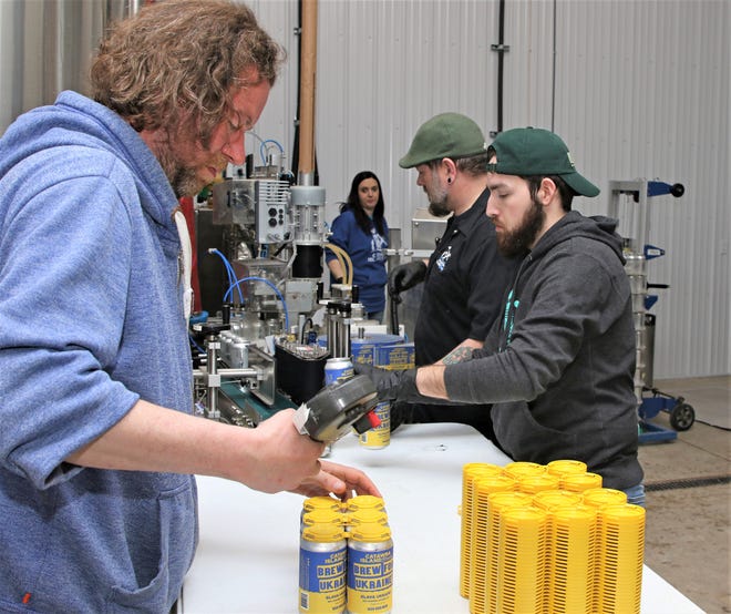 Catawba Island Brewing Co. workers can Slava Ukraini, a unique beer created from a Ukrainian recipe, on Wednesday. Sales will benefit Ukraine relief efforts.