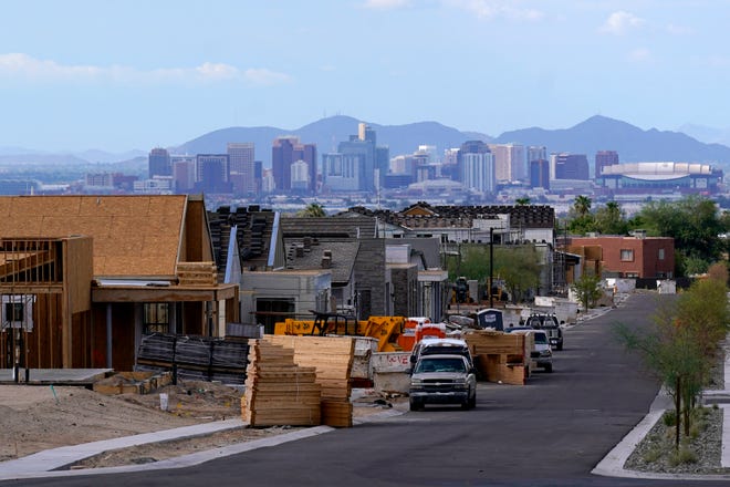 With the downtown skyline in the background, a new housing development adds to the expansive urban sprawl continuing to grow, Aug. 12, 2021, in Phoenix.
