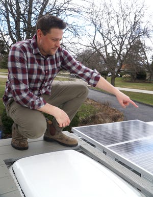 Nick Koknus points out the three 100-watt solar panels that the couple installed on the roof of their truck.  When it's sunny, you should keep the truck's batteries well charged.