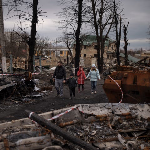 A family walks amid destroyed Russian tanks in Buc