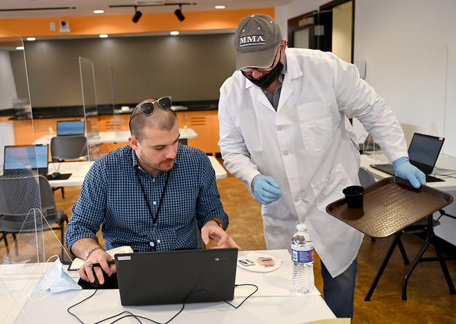 Field technician Allen Bohnert, right, gives Daily News reporter Toni Caushi a sample of cheese puffs at Curion, a new consumer packaged goods taste-testing facility in Natick, April 8, 2022.