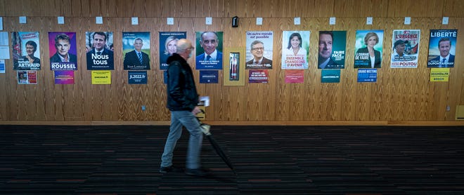 A French voter passes identification posters on his way to vote in the first round of the 2022 French presidential election, in Montreal, Saturday, April 9.