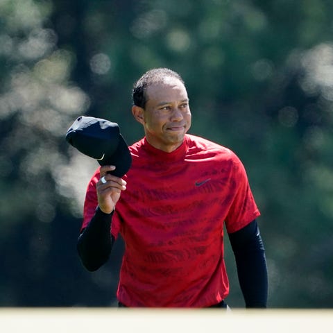 Tiger Woods tips his hat to the fans as they appla