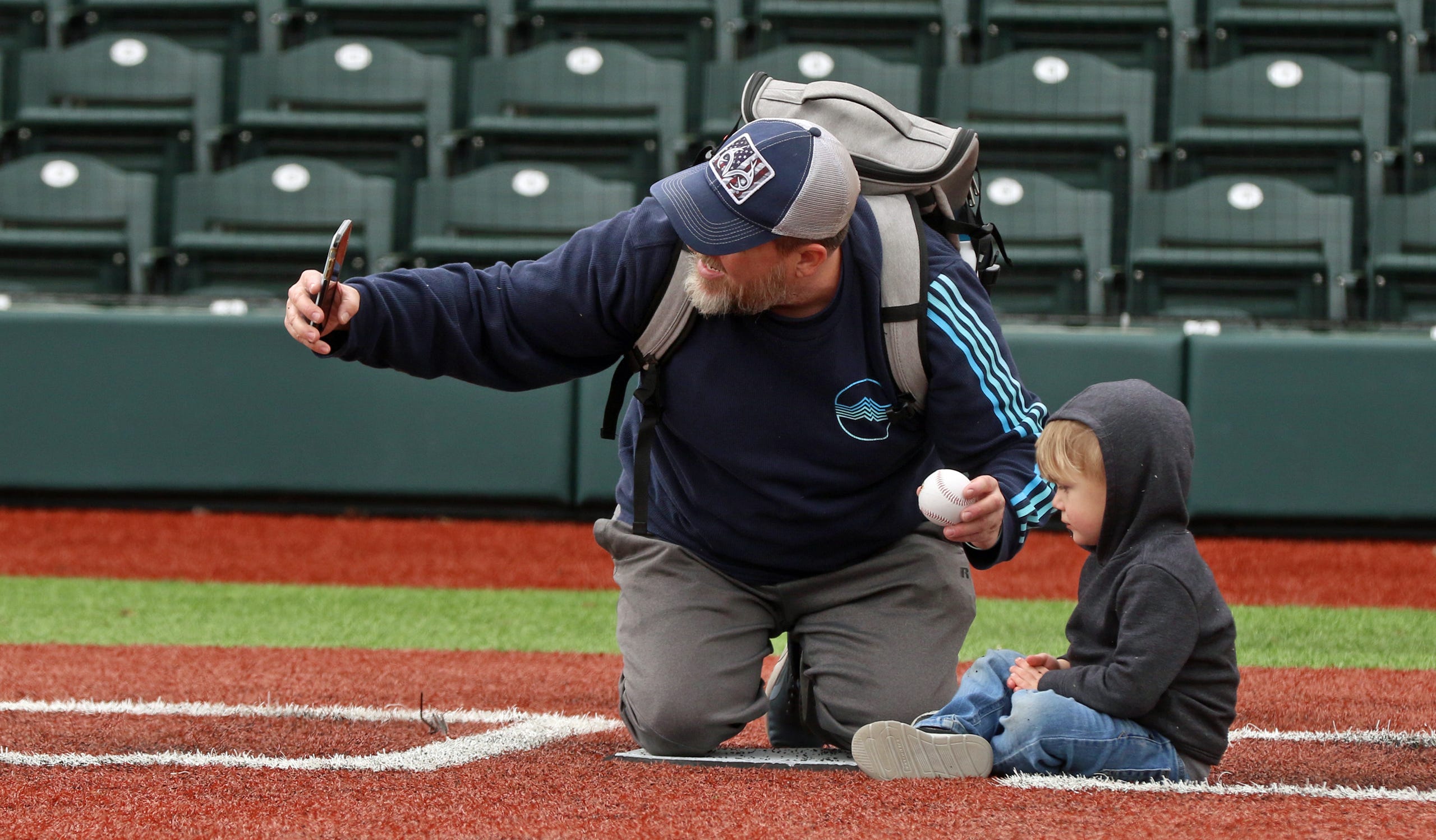 Robert Lugo takes a photo of himself and his son, two-year-old Ashton Lugo, at home plate during the Honey Hunters Community Day held Saturday, April 9, 2022 at CaroMont Health Park.