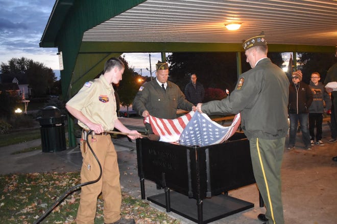 Orion Cub Scout Pack 123 gathered on Monday, Nov. 1, at the Lions Club picnic shelter in Central Park to learn how to retire American flags that are showing their age. Orion Boy Scout Nick Shillington, left, applies flame to a flag held by Orion VFW Post 143 members Kevin Johnson, center, and Scott Peterson, right.