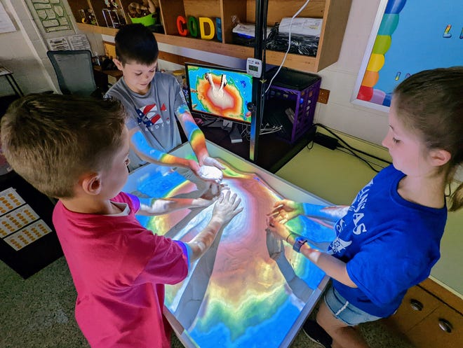 Fifth-graders Kaeson Kruger, Logan Keen and Rylin Kirkwood pile up sand to create the Kansas-version of Mount Everest on Monday at Silver Lake Elementary School.