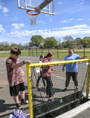 Kam Standard, left, his sister K.K. Standard, and mother Keri Standard, right, look at a net at the Over Under court in Wellington Park, off of South Main  Street extension below Homeland Park in Anderson. Anderson County dedicated the multipurpose court for basketball and street hockey, complete with new asphalt, goals, and retractable goals with nets in April 2022. 