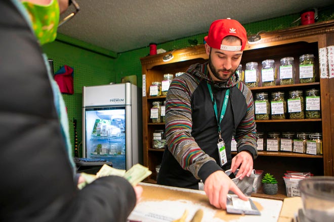 Jed Sadloski, right, helps customer Kate Porte at Lionheart Cannabis in Billings, Mont., during the opening day of legal recreational marijuana sales in Montana on Jan. 1, 2022. Recreational cannabis sales have totaled more than $43.5 million so far this year, setting Montana on track to reach $174 million by the of the year. (Ryan Berry/The Billings Gazette via AP)