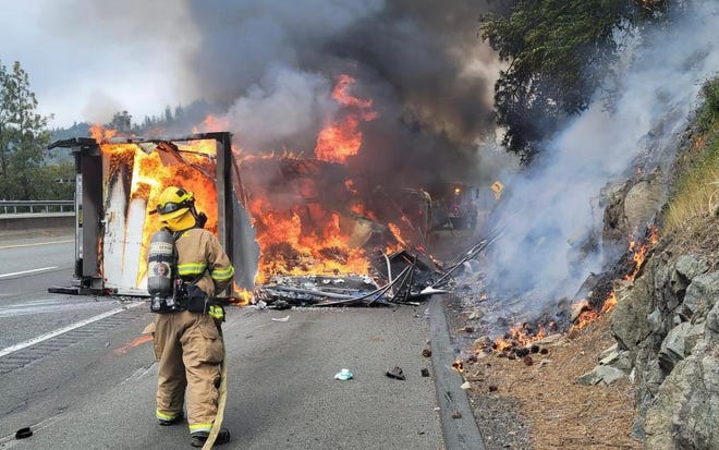 Firefighters work to extinguish flames after a big rig overturned and caught fire on northbound Interstate 5 near the Bridge Bay exit in Mountain Gate on Tuesday afternoon, April 12, 2022. The driver died in the crash, the California Highway Patrol said.