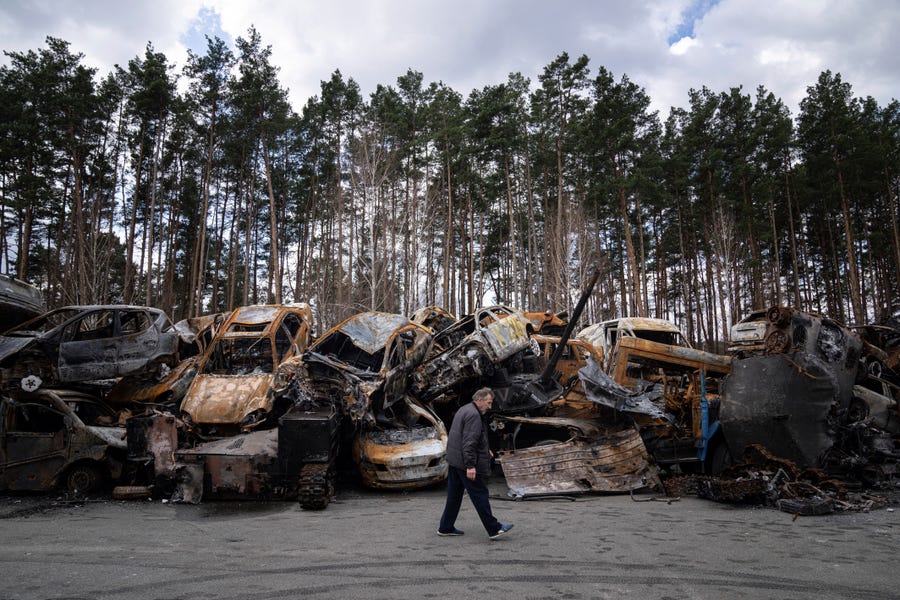 A man walks past a storage place for burned armed vehicles and cars, in the outskirts of Kyiv, Ukraine, Monday, April 11, 2022.