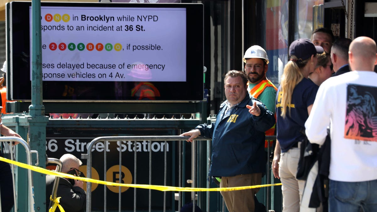 Members of the NYPD work at the scene of a subway shooting in Brooklyn April 12, 2022 where at least ten people were shot during the morning rush hour. 