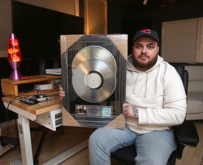 Franky Wahoo, the musical artist name of beatmaker Franklin Stewart, displays his platinum record from his work with Machine Gun Kelly in his music studio in North Canton on Tuesday, April 12, 2022. 