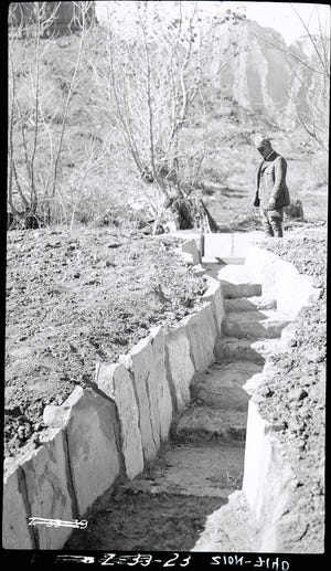 Irrigation ditches in Zion National Park with a ranger looking at water drops, 1930s.