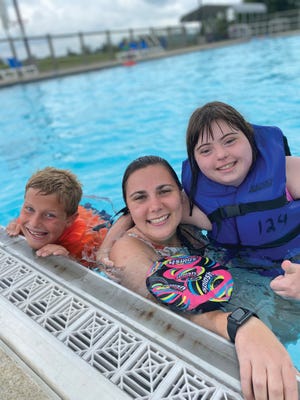 A Recreation Unlimited counselor and two campers swim in the lap pool.