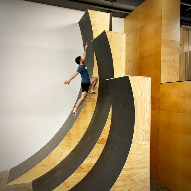 An athlete scales a warped wall style obstacle at ROAM Further Athletics in Mount Kisco.