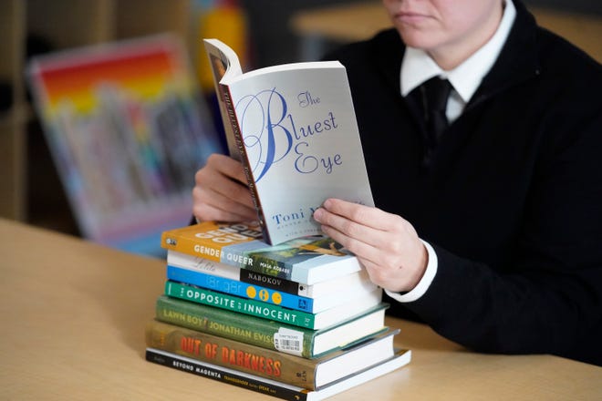 Amanda Darrow, director of youth, family and education programs at the Utah Pride Center, poses with books, including "The Bluest Eye," by Toni Morrison, that have been the subject of complaints from parents in Salt Lake City on Dec. 16, 2021.