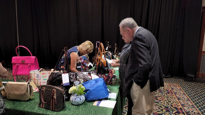 A couple looks over purses at the Power of the Purse charity event Thursday at the Amarillo Civic Center.