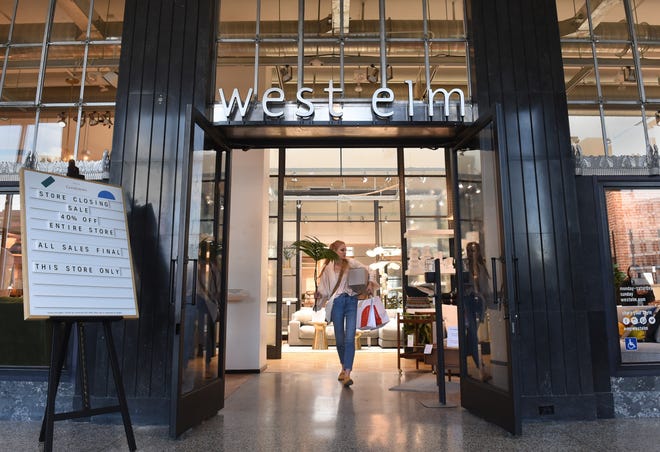 A customer walks out of the West Elm furniture store in downtown Reno after purchasing items in a store closing sale on April 15, 2022.