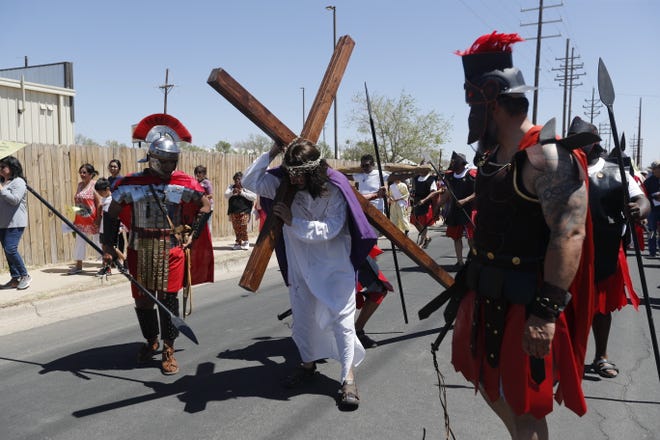 An actor portraying Jesus carries the cross as he makes his way during the Stations of the Cross ceremony at the Our Lady of Grace Catholic Church Friday, April 15, 2022.