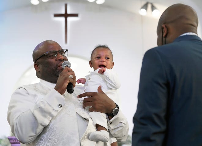 Ace Nelon Russell, 5 months, is all smiles after being baptized by the Rev. Victor M. Davis, pastor of the Trinity Baptist Church, during Easter service Sunday. Ace is the son of William (right) and Lacey Russell, of Gahanna, who have two older children, William Russell IV, 4, and Lynda Russell, 2. To see more photos, go to Dispatch.com.