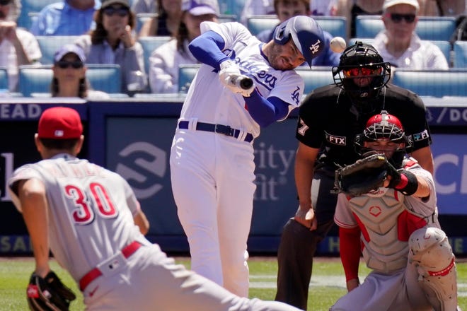 Los Angeles Dodgers' Freddie Freeman, second from left, hits a single as Cincinnati Reds starting pitcher Tyler Mahle, left, watches long with catcher Tyler Stephenson, right, and plate umpire Jim Reynolds during the fourth inning of a baseball game Sunday, April 17, 2022, in Los Angeles.