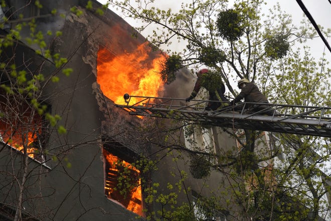 Petugas pemadam kebakaran bekerja untuk memadamkan api di sebuah gedung apartemen setelah serangan Rusia di Kharkiv, Ukraina, Minggu, 17 April 2022. (AP Photo/Andrew Marienko)