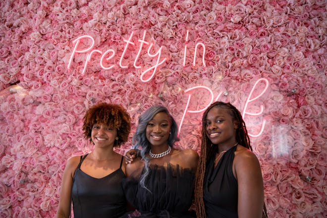 Ο Nevah Jones, αριστερά, η Ashley Walker και η Nariah Woods ποζάρουν για φωτογραφίες μπροστά από τον όμορφο φωτογραφικό τοίχο του Pink Factory στο The Sugar Factory κατά τη διάρκεια του Σαββατοκύριακου εγκαινίων, Σάββατο 16 Απριλίου 2022 στο κέντρο της Indianapolis.  Γιορτάζουν τα δέκατα έβδομα γενέθλια της Ashley.