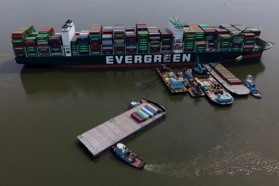 Tugboats, bottom, align a barge near the container ship Ever Forward, top, which ran aground last month, as workers remove containers from it in efforts to lighten the load and refloat the vessel, Wednesday, April 13, 2022, in Pasadena, Md. The ship has been stuck in the channel since March 13.