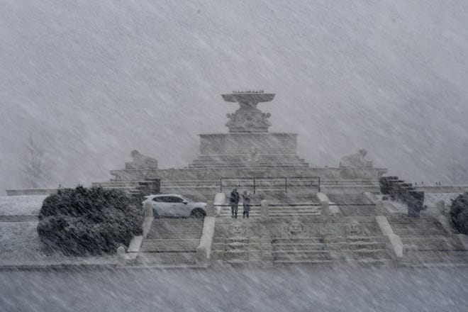 Jose Arellano and Reina Ramos take some pictures  in front of the Belle Isle fountain as slushy flurries pour down on metro-Detroit, Michigan on April 18, 2022.  (Image by Daniel Mears/ The Detroit News). 