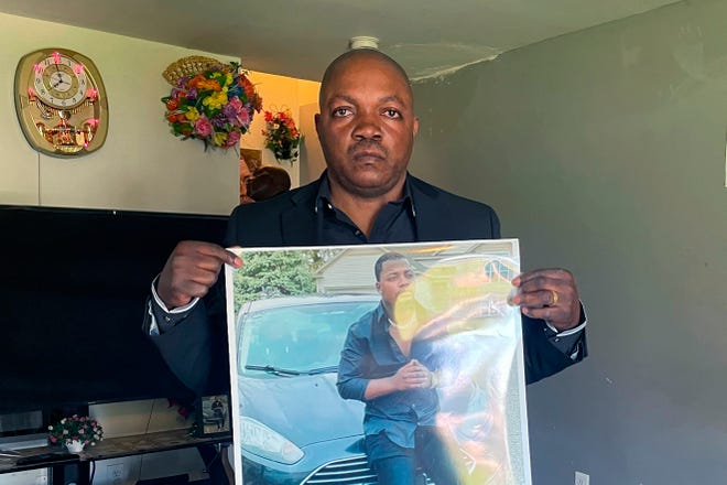 Peter Lyoya holds up a picture of his son Patrick Lyoya, 26, in his home in Lansing, Mich., April 14, 2022.
