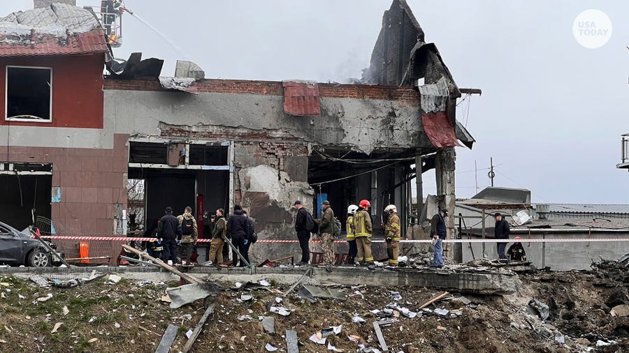 Emergency workers clear up debris after an airstrike hit a tire shop in the western city of Lviv