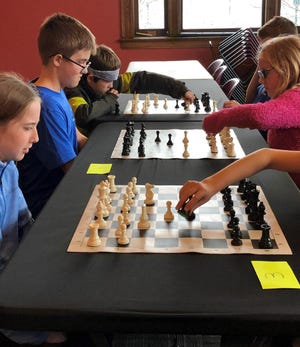 Chess club members are seen in action combating each other in the game.