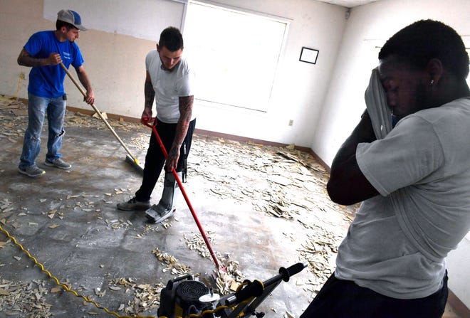 James Griffin wipes his face as he and brothers Austin (left) and Colton Perkins remove tile from the Pine Street Goodwill store location Tuesday. The resale shop is undergoing renovation and will reopen in the near future.