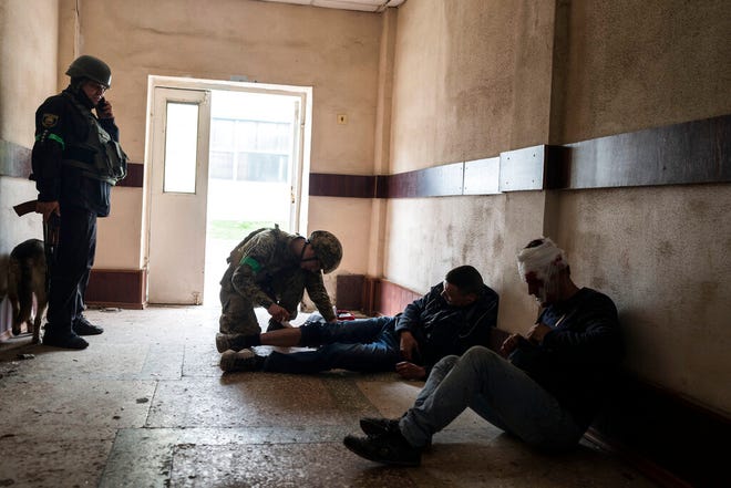 A member of security forces gives first aid to an injured man following a Russian bombing of a factory in Kramatorsk, eastern Ukraine, Tuesday, April 19, 2022, killing at least one person and injuring three others.