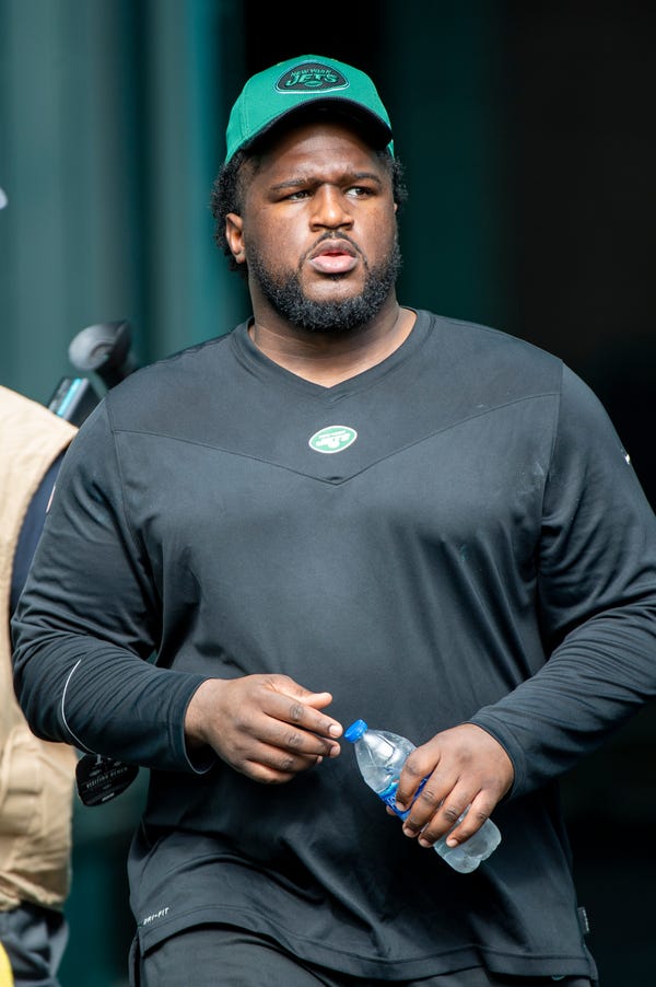 Nate Ollie, then a New York Jets assistant defensive line coach, walked  onto the field before an NFL football game against the Miami Dolphins, Sunday, Dec. 19, 2021, in Miami Gardens, Fla. (AP Photo/Doug Murray)