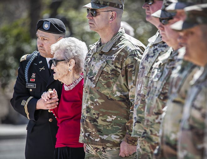 Ann Overmier, 92, whose late husband Bill Overmier was a survivor of the Bataan Death March, quietly sings "Amazing Grace" as her escort, Maj. Francisco Cazares, lends his support Saturday, April 16, 2022, during the state National Guard's 80th anniversary commemoration of the fall of Bataan.