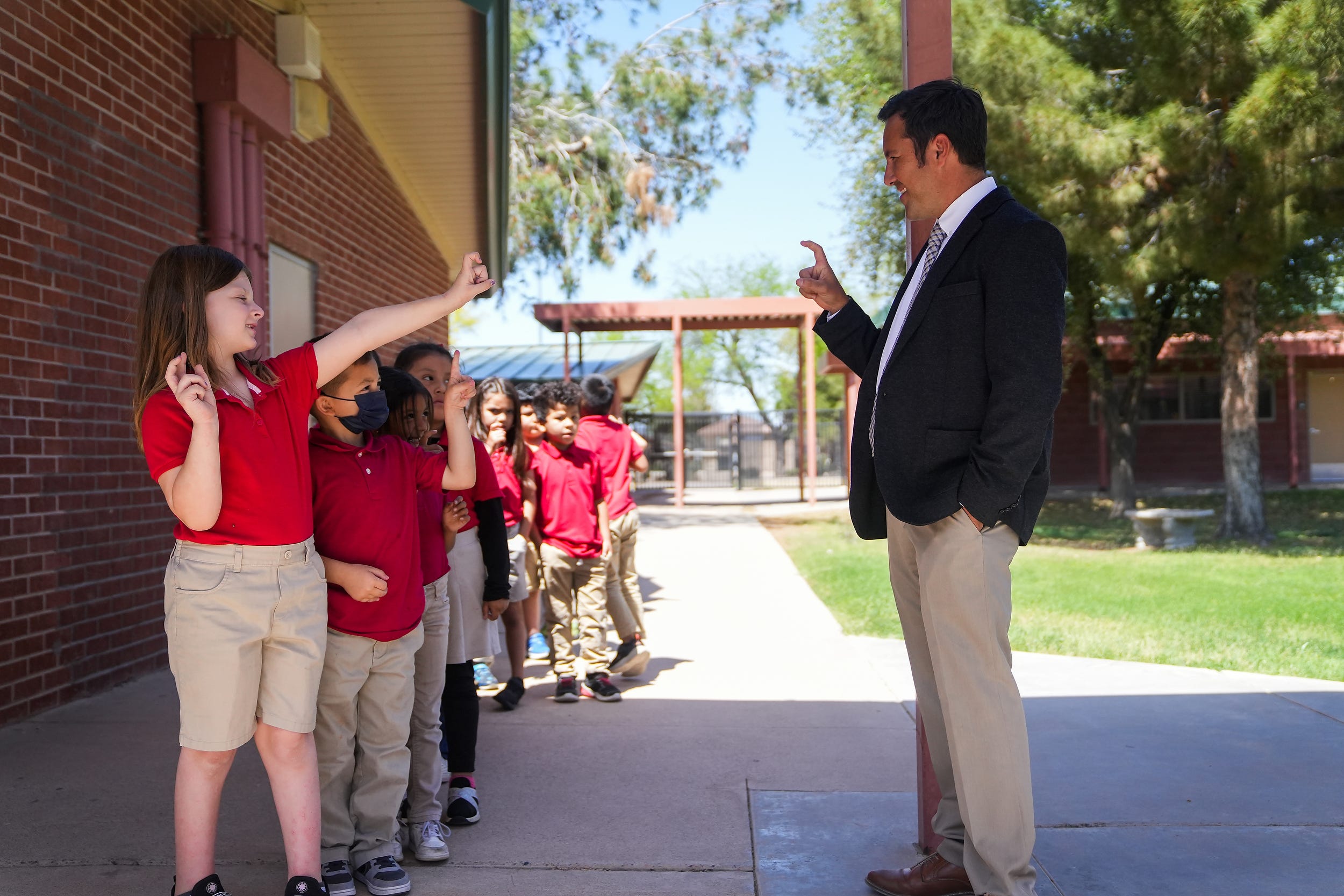 Ashlynn Shoemaker, 6, greets Tony Alcala, principal of Galveston Elementary School, as the kindergarten class makes its way back to class after recess at Galveston Elementary School on April 6, 2022, in Chandler.