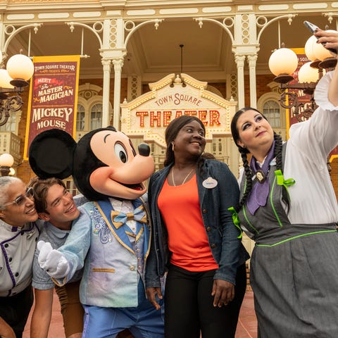 Mickey Mouse poses for a selfie with cast members 