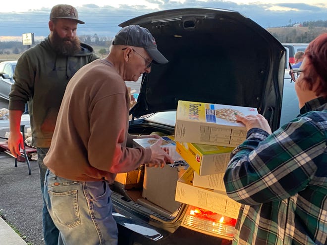 Volunteers with the Ozark Church Food Pantry load donations into a vehicle outside Ozark Free Will Baptist Church, located at 8414 Puddin Ridge Road.