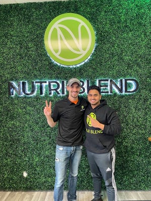 Owner Cory Wunrow (left) and his "silent financial partner" Faisal Farooqui stand in front of the Nutri Blend logo inside their new Franklin smoothie shop.