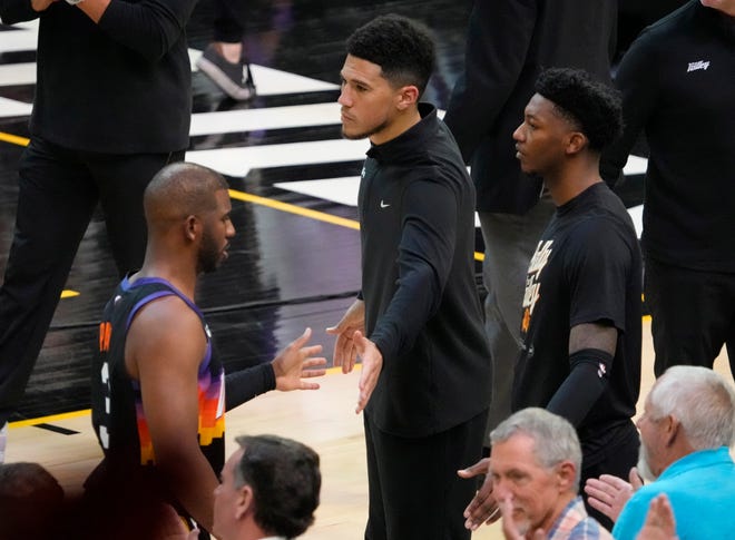 Apr 19, 2022; Phoenix, Arizona, U.S.;  Phoenix Suns guard Devin Booker (1) slaps hands with Phoenix Suns guard Chris Paul (3) while watching the fourth quarter from the bench during Game 2 of the Western Conference playoffs against the New Orleans Pelicans.