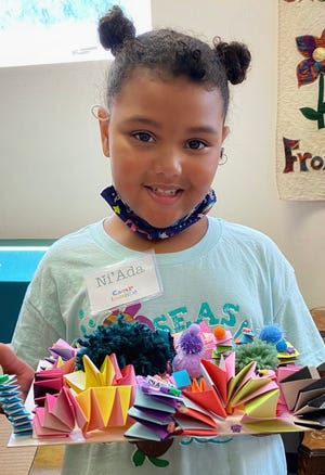 Camper shows off finished paper sculpture at Camp Imagine.