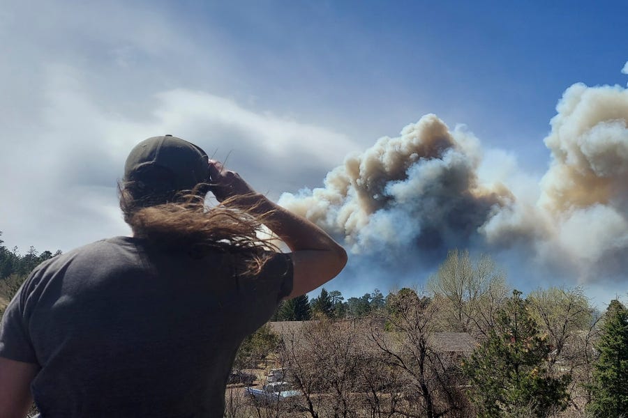 Smoke from a wind-whipped wildfire rises above neighborhoods on the outskirts of Flagstaff, Arizona, on Tuesday, April 19, 2022.