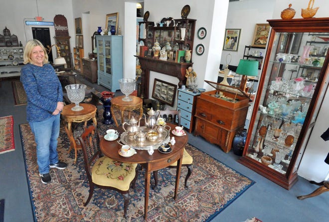 Anne Marie Kelly, owner of Bridge Antiques, stands among some antiques and collectibles in her North Weymouth store, Tuesday, April 19, 2022.